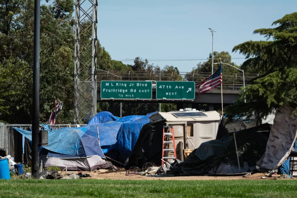 Encampment of unhoused people in Sacramento, California with freeway in the background